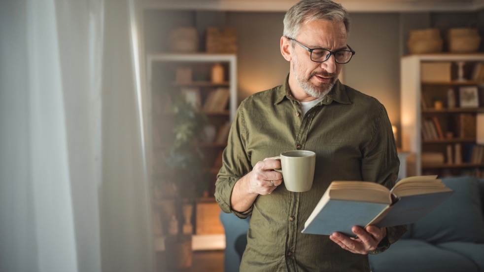 Man with a coffee reading a book